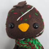 Close-up of Chocolate Cake Penguin face with icing and sprinkles on a white background.