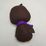 Chocolate Penguin back with a purple scarf on a light gray background