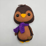 Chocolate Penguin plush with a purple scarf on a white background