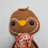 Brown plush gingerbread penguin face on a white background