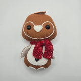 Stuffed plush gingerbread penguin with white features and a red scarf on a light gray background
