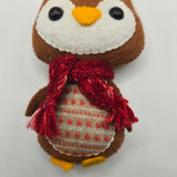 Small plush Gingerbread Penguin body with a red scarf and stomach with red ball patterns and white line patterns on it on a light gray background