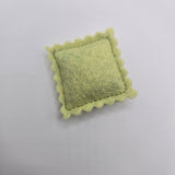 Green textured ravioli on a light gray background