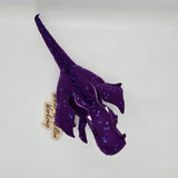 Handmade purple felt dragon plush with a light lavender belly, small white horns, and black button eyes. The dragon is decorated with shimmering sequins across its head, wings, and body.