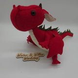 Handmade red felt dragon plush with white wings, small horns, and black button eyes. The soft stuffed dragon stands upright with a curved tail and stitched details.