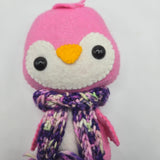 Pink penguin face with a multicolored purple scarf on a white background