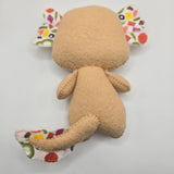 Stuffed axolotl toy with pizza topping ears and tail on a light gray background