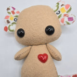 Small brown plush toy with colorful pizza topping patterns on a white background