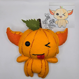 Handmade pumpkin gremlin felt plush with an orange pumpkin body, pointy ears, and stitched pumpkin lines. The character has one black button eye, a winking stitched eye, and a playful tongue sticking out with a small green leaf and stem on top.