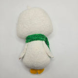 Small plush white penguin with a green scarf on a light gray background