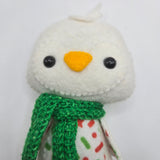 Close-up of a white penguin face and a green scarf on a white background.